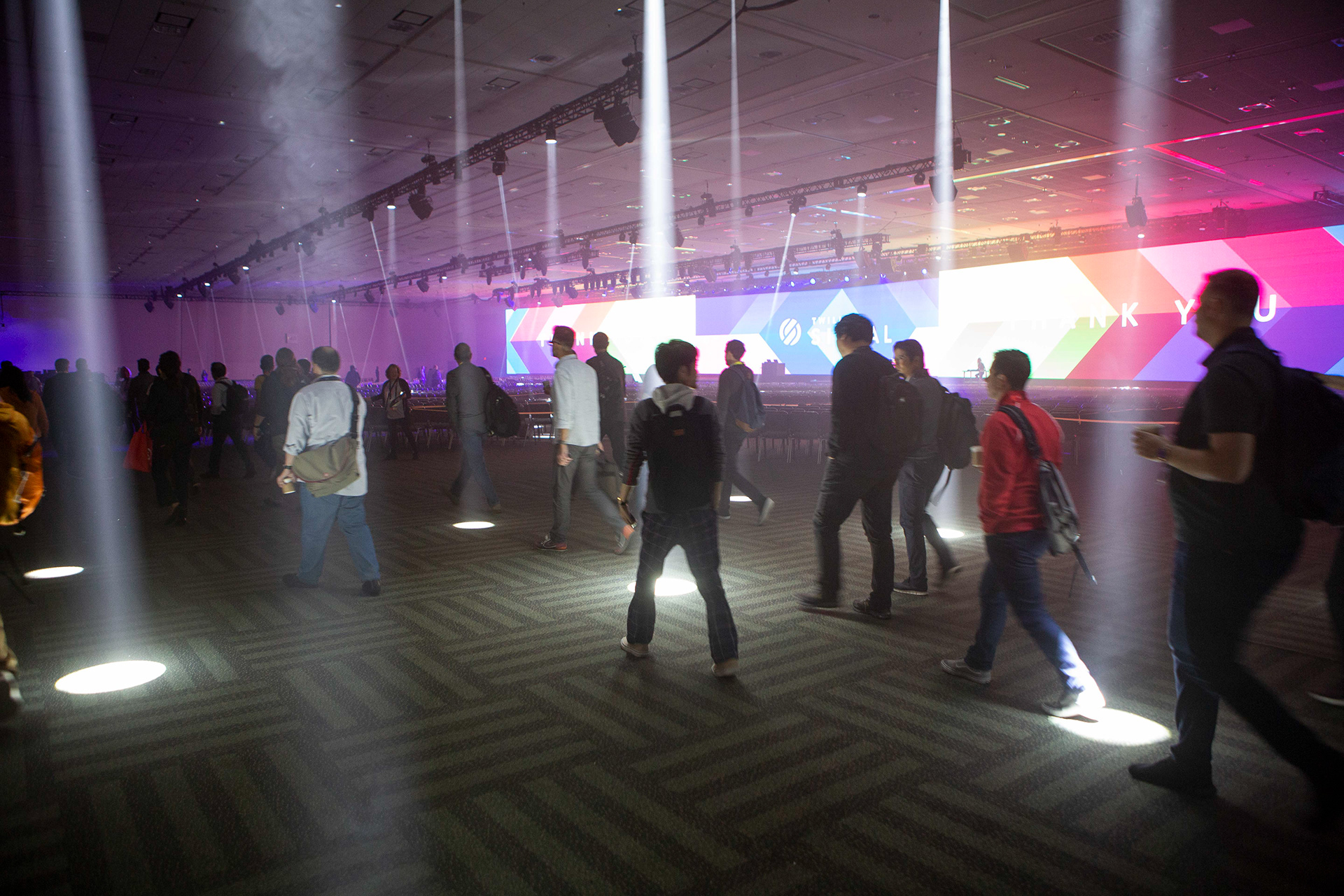 Attendees walking through fog and colored lighting in large convention center venue